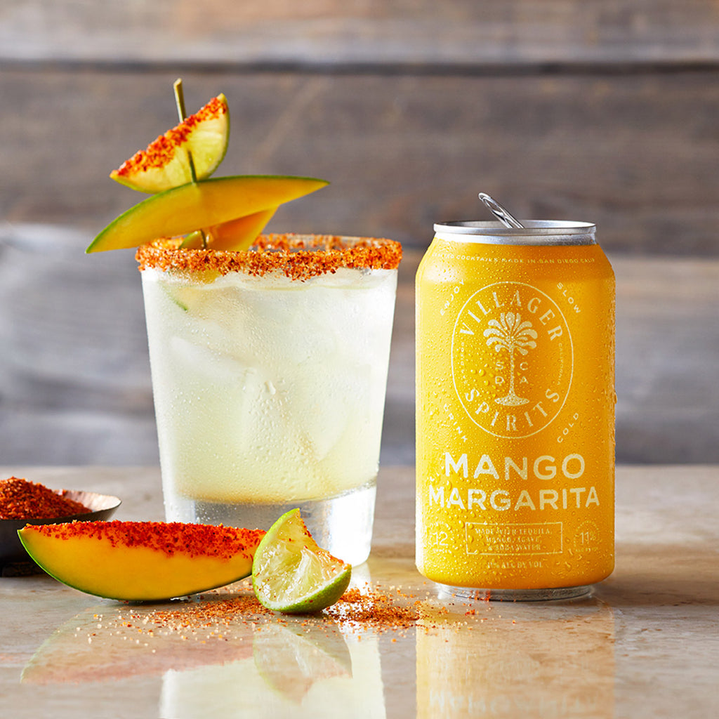 Villager Spirits Mango Margarita craft cocktail garnished with fresh mango and lime slices and a Tajin spiced rim.